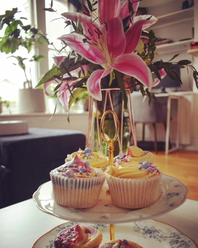 Pastel cupcakes on a gold-handled cake stand in warm afternoon light