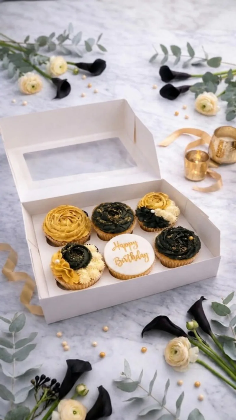Black and gold rose cupcakes with a Happy Birthday disc, styled with ranunculus, black calla lilies and gold candles